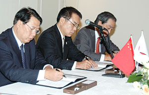 調印書にサインする瓮福・董事長（左）とＪＡ全農・神出常務（中）