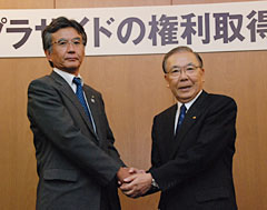 会見後、握手する山崎常務（左）と石原社長