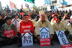 与党の強行採決に抗議する農民団体（2011年11月22日）。プラカードには「韓米ＦＴＡ無効」「李明博（当時の大統領）政権退陣」などの文字。前列の人は葬儀の服装で抗議