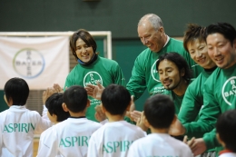 子どもらとハイタッチする細貝選手（左）。隣はハンスディーター・ハウスナー日本バイエル社長。