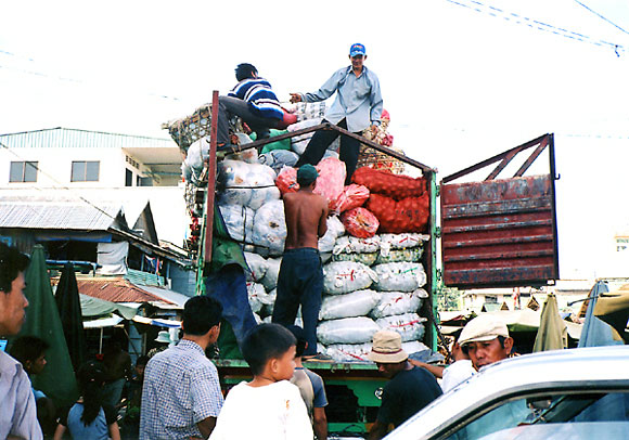 仲買商人がベトナムから野菜を小売市場に持ってくる