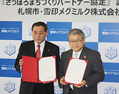 ３月７日の調印式にて。上田市長（写真・右）と中野社長。