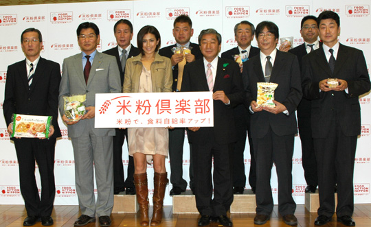 推進パートナー代表８社と、米粉倶楽部の看板を掲げる赤松農相（前列右から３人目）と長谷川理恵さん（同４人目）