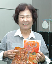 松岡ヨシ子さんと人気商品の柿チップス