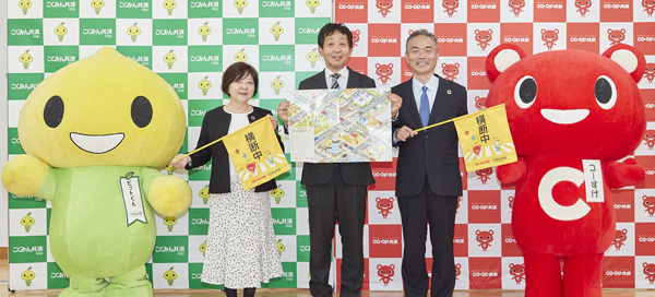 横断旗寄贈に臨んだこくみん共済coopの蛭田美幸常務理事（左）、井熊校長（中央）、コープ共済連の石川勝也常務理事（右）