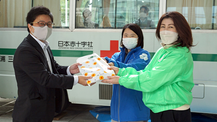 献血協力者（左）にプレゼントを渡す東京ガーデンテラス紀尾井町職員（中央）とＪＡ共済連職員
