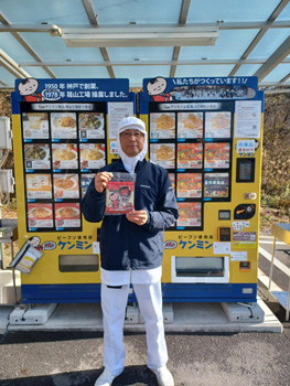 篠山工場前冷凍自販機と主力商品「焼ビーフン」を手にする工場長