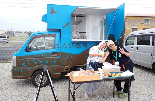 漁港朝市に出店した小林さんのキッチンカー「とんび茶屋」。右は料理長の美香さん。この日はおにぎり各種、汁物のほか、野菜を売った。
