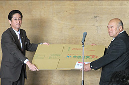 贈呈式でダンボールを受け取る高城組合長（右）と黒田部長