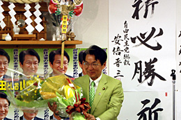 花束を受け取り笑顔で抱負を述べる山田俊男議員