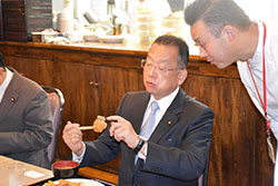鹿肉メンチカツについて話す山本大臣（左）と藤木理事