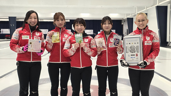 「ニッポンの食」を手に笑顔のカーリング女子日本代表選手（提供：日本カーリング協会）