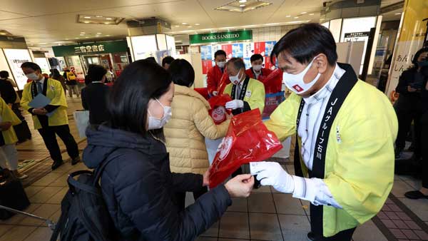 「ひゃくまん殻」のおにぎりを無料配布する馳知事（右）