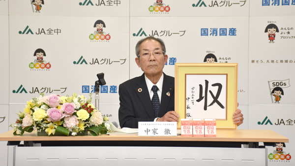 「収」の文字を掲げる中家会長