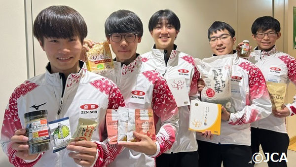 「ニッポンの食」を手に笑顔のカーリングジュニア日本代表チームのメンバー