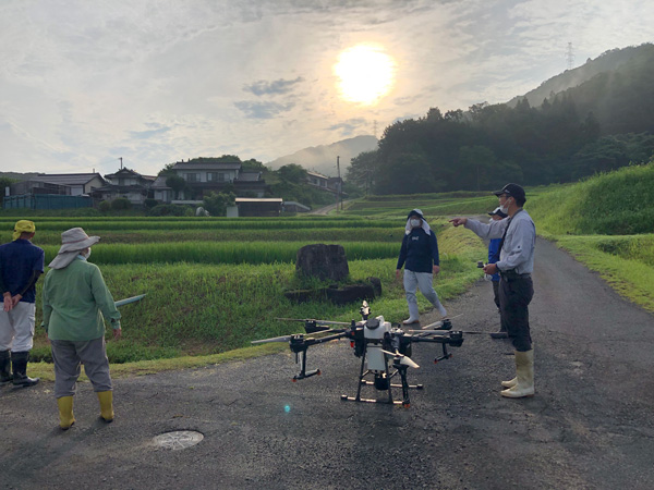 鍋山農作業センターの代表石原公夫さん（右）、ご子息の睦大さん（中）、奥様の和美さん（左）は、家族総出でＴ20　1台を使い請負防除を行っている。