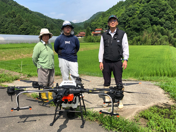 朝日が昇った直後の風のない早朝に作業を行う。中山間地特有の段になった田んぼを前に作業手順の確認を行う。