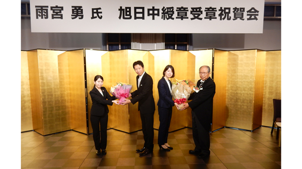 花束を受ける雨宮勇氏（右端）とご子息の一路氏（右から3番目）