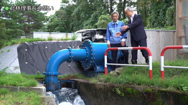 小水力発電所と北林理事長（右）と和久社長（秋田県にかほ町で）