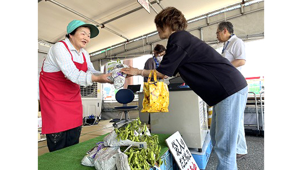 お客様にだだちゃ豆を手渡す菅原会長（左）