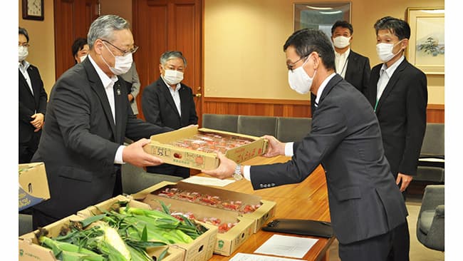 澤井会長（写真左）が寄付のサクランボを若林副知事に手渡した（山梨県甲府市）