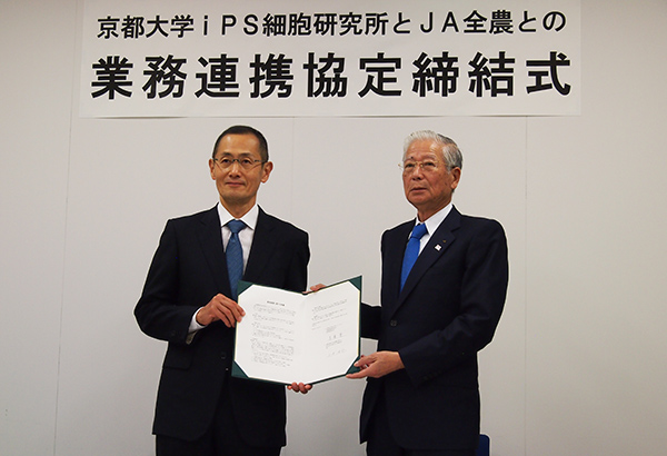 署名した業務連携契約文書を持つ、山中伸弥教授（左）と長澤豊会長