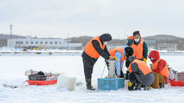 網走能取湖氷上で水産資源の調査を行う西野教授と学生達