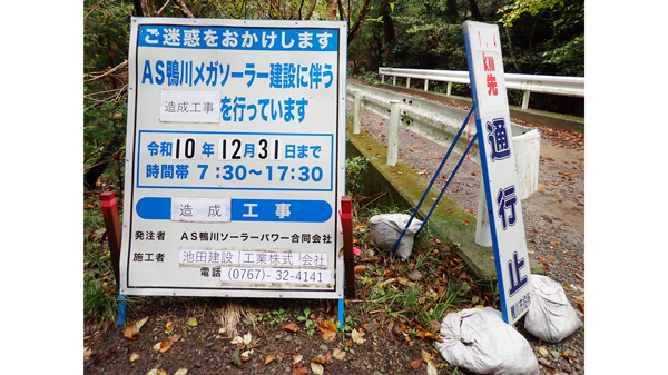 鴨川メガソーラー工事現場への入り口には林地開発許可の標識と通行止めの看板があった。施工者が最近変わったため、紙が貼られている。