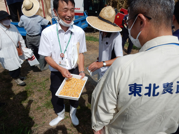 実証試験ほ場で収穫された飼料用とうもろこし（子実）に思わずにっこりする関係者