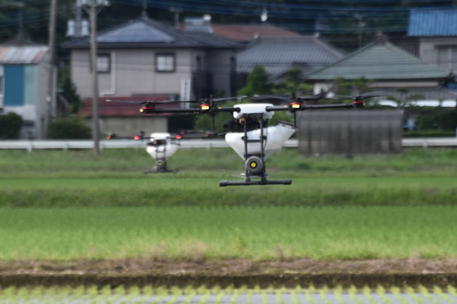 20190627　ヘッドライン　整然と農薬を散布するドローン2機の編隊飛行