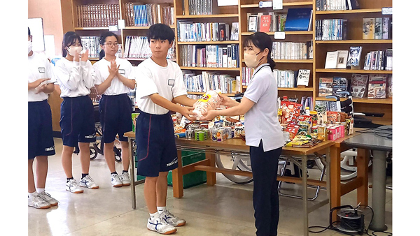 寄贈式で食品を手渡す生徒（昨年度）