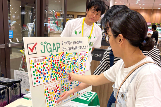 JGAP7つの取り組みから関心のある項目を選ぶシールアンケートに参加する来場者