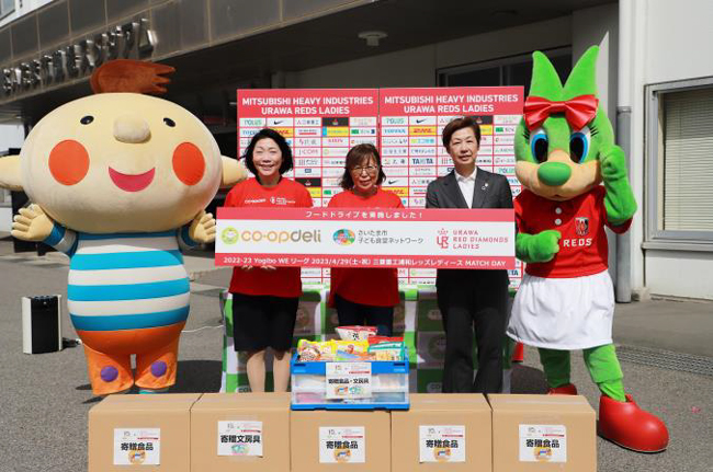 フードドライブイベントで寄せられた食品と文房具の寄贈式。右から、浦和レッドダイヤモンズの藤倉佳子氏、さいたま市子ども食堂ネットワークの本間香代表、コープみらい 新井ちとせ理事長