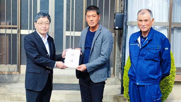 生活クラブ連合会 の村上彰一会長から古川りんご園の古川元祥代表（中央）と同園の花田敏英氏に災害見舞金を届けた