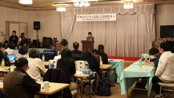 持続可会場に集う参加者に監査報告をする監査人