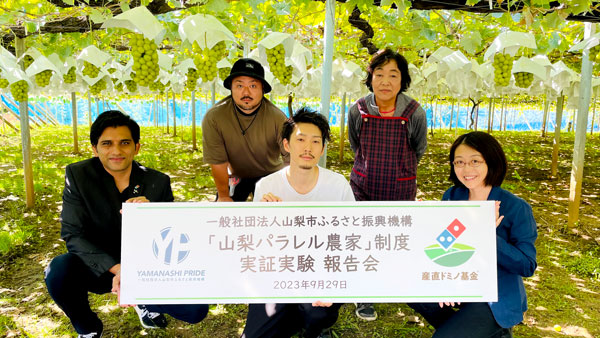 一列目左から　ドミノ・ピザ ジャパンのムリナル・シンハCMO、山梨市ふるさと振興機構代表の田中友悟さん、 産直ドミノ基金の松原歩代表理事、二列目左から日森康浩さん、日森清美さん（山梨市）