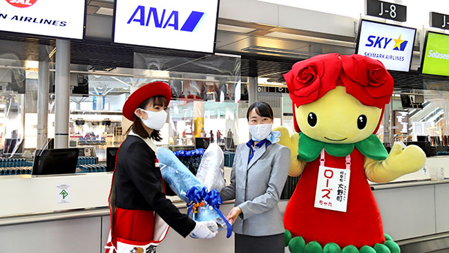 ANAスタッフにバラの花束を手渡すおおの親善大使の宮川さん（写真左）