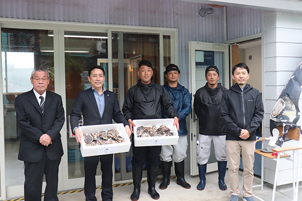 初出荷を迎えた「鶴宝」を手にする松本町長（左から二人目）、岩ガキBASEの皆木代表（同三人目）とプロジェクトのメンバー