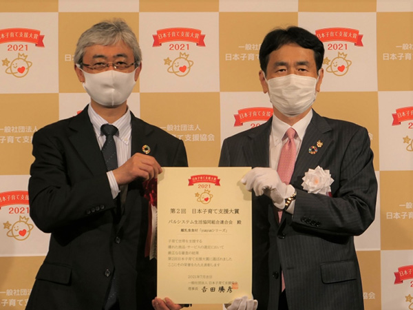 日本子育て支援協会の吉田委員長（右）から表彰状を受け取るパスシステム連合会の大信理事長