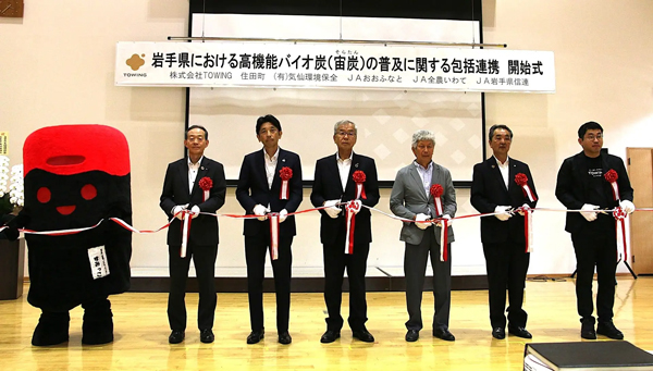 開始式のテープカット。左から住田町の公式キャラクター「すみっこ」、ＪＡ岩手県信連　工藤孝志代表理事専務、ＪＡ全農いわて　佐竹雅之副本部長、ＪＡおおふなと　猪股岩夫代表理事組合長、気仙環境保全 　大和田国弘代表取締役、住田町び神田謙一町長、TOWING西田宏平CEO