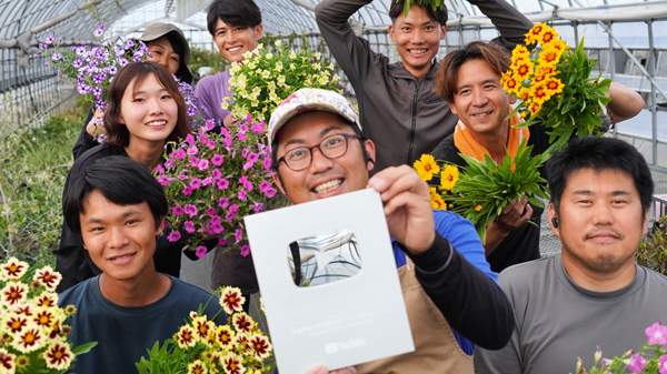 10万人達成の銀の盾を持つ村岡代表と社員