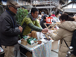 狭い路地の展示場で豆を味わう人たち